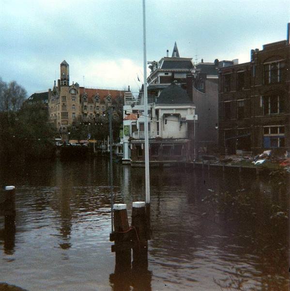Amsterdam canal houses reflected in the water under a grey sky