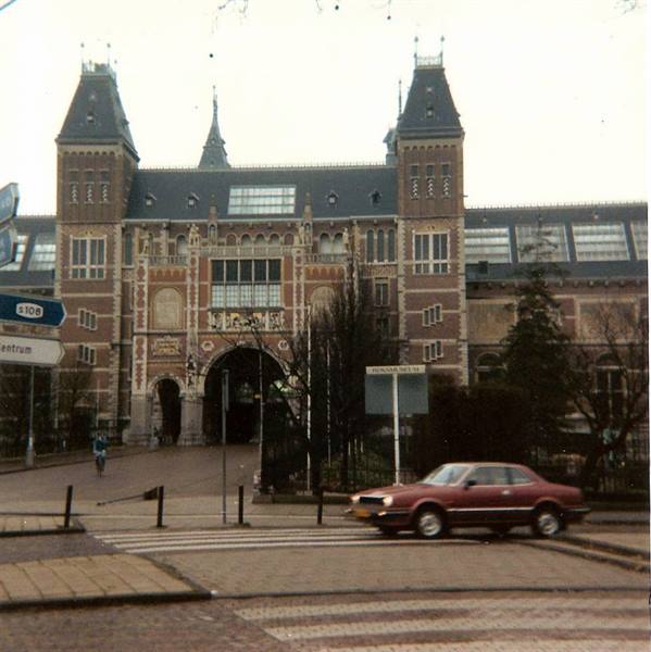 Red car passes in front of the Rijksmuseum, Amsterdam, grey morning