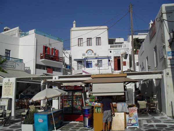 Drink kiosk among whitewashed Cycladic houses with colorful balconies, Mykonos