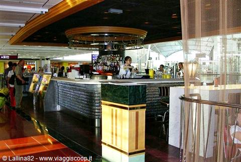 Mosaic bar counter with bottles behind, inside an airport terminal