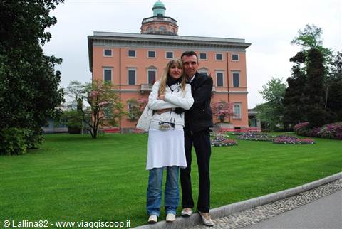 couple hugging on the lawn in front of a historic pink villa
