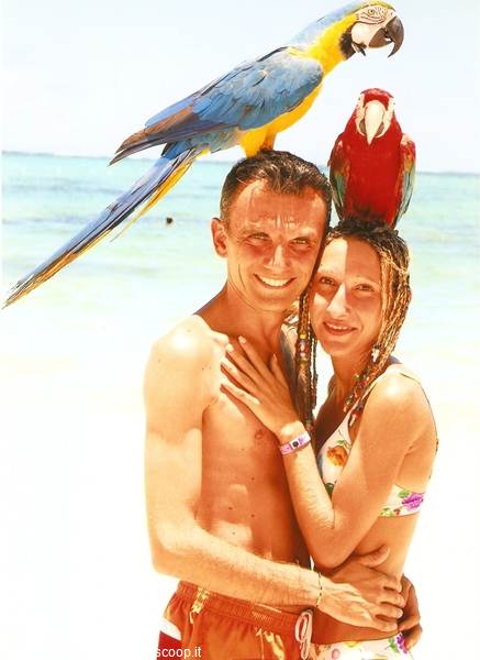 Couple on the beach with blue and scarlet macaws on their heads
