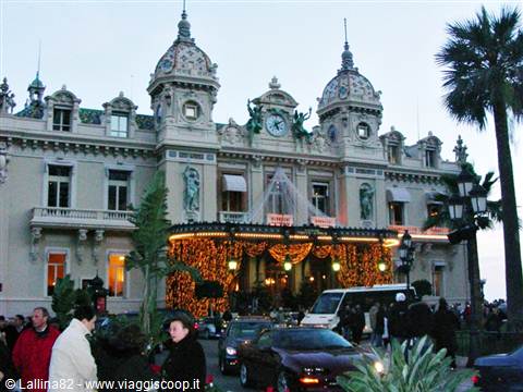Monte Carlo Casino lit up at night, with clock, domes and crowd