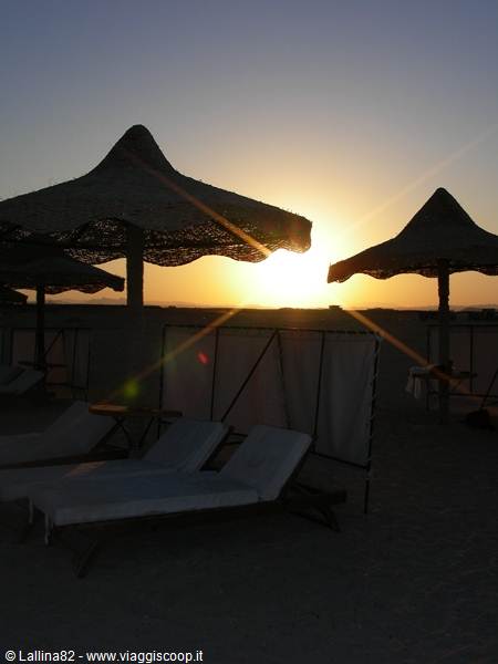 Straw umbrellas and empty sunbeds on the beach at sunrise