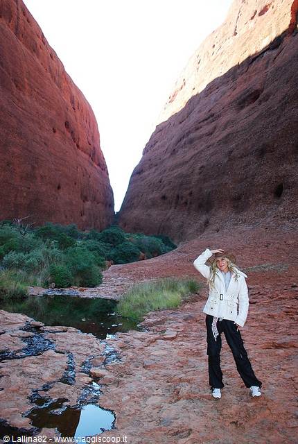 Blonde tourist posing among red rock walls of Walpa Gorge, water pools