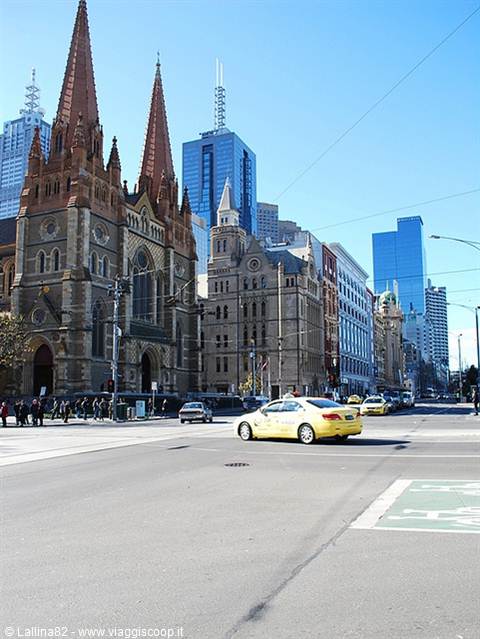 St Paul's Cathedral in Melbourne, yellow taxi crosses the intersection under blue sky