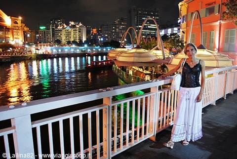 Tourist on white bridge at night in Clarke Quay, Singapore, river lights