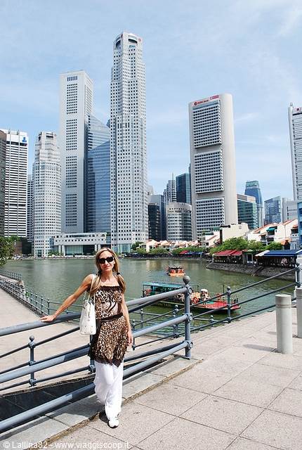 Woman leaning on Boat Quay railing, skyscrapers over the river, boats passing