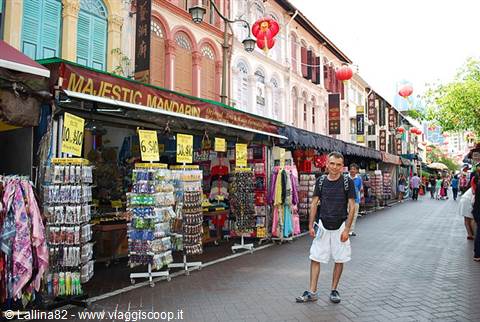 Tourist walks past souvenir stalls in Singapore's Chinatown under red lanterns