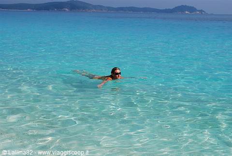Woman swimming in clear turquoise water, island in the background