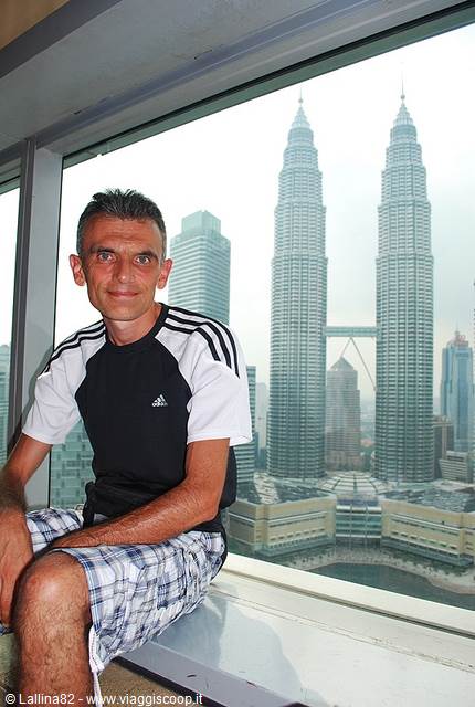 Smiling tourist in front of the Petronas Towers seen from a panoramic window