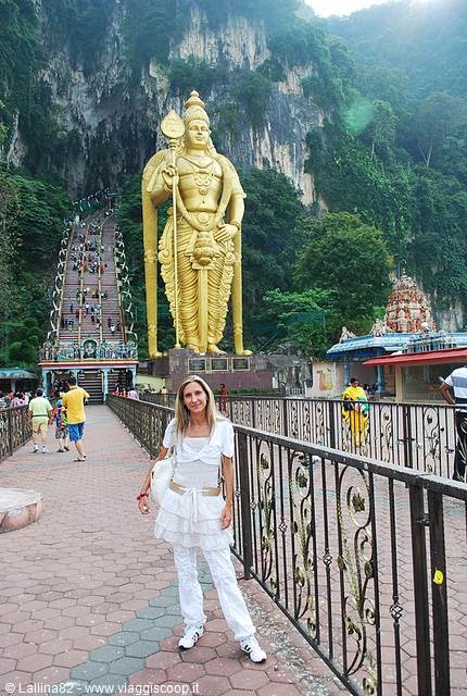 Tourist in white in front of the golden Murugan statue, Batu Caves