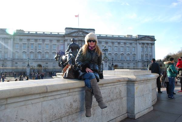 Tourist sitting on a marble wall in front of Buckingham Palace, London