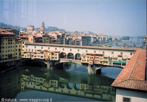 Ponte Vecchio in Florence, colorful shops on the Arno, reflected in still water