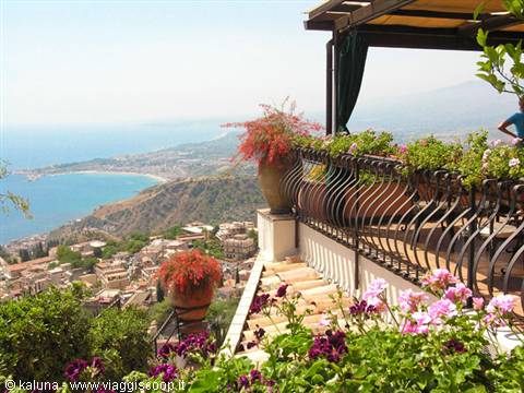 Flower-filled terrace with wrought iron railing over Taormina's sea