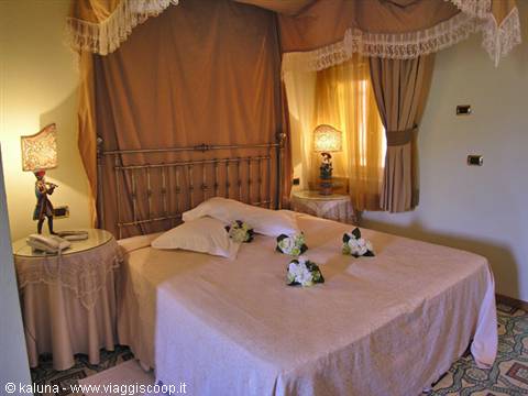 Hotel room with brass canopy bed and white roses on the bed