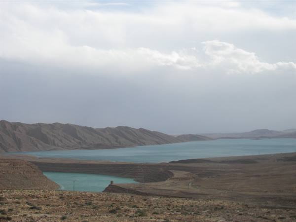 Turquoise water between arid mountains under cloudy sky