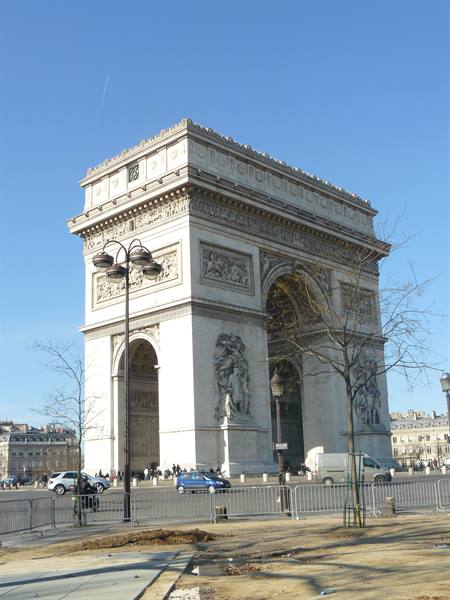 Arc de Triomphe in Paris, pale stone under blue sky, traffic below