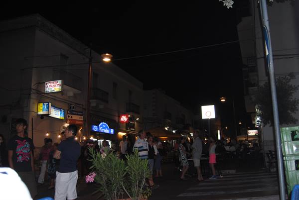 Tourists stroll at night among illuminated shop signs on the street