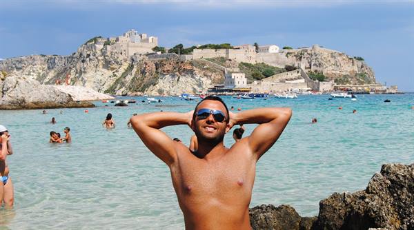 Man in sunglasses relaxing by turquoise sea, Tremiti Islands
