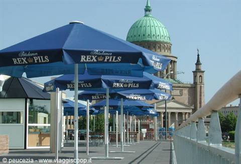 Blue Rex Pils umbrellas along the river in Potsdam, Nikolaikirche green dome behind