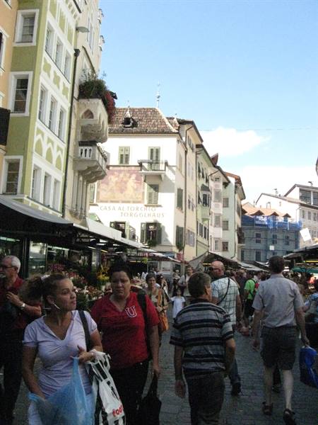Shoppers walk past flower stalls at Obstplatz square in Bolzano
