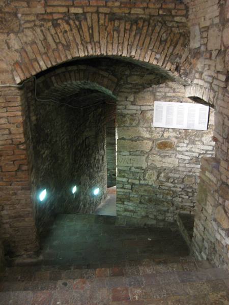 Brick staircase beneath a barrel vault, small lights glowing on stone walls