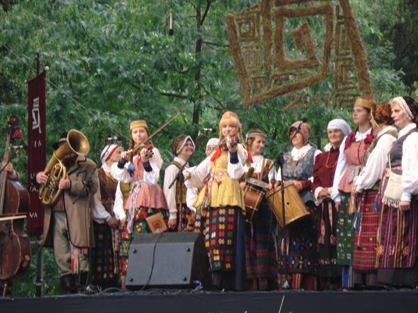 Musicians in traditional folk costumes with horns and drums on festival stage