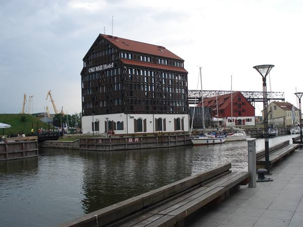 Old Mill Hotel timber building by the harbor with moored yachts and benches
