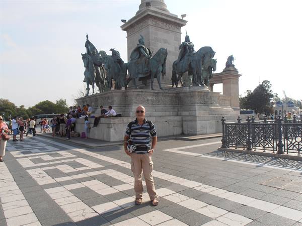 Smiling tourist in front of the bronze horse statues at Heroes' Square, Budapest