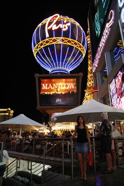 Paris hotel balloon neon sign, white umbrellas and visitors at night in Las Vegas