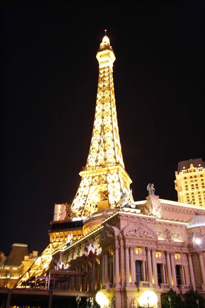 Illuminated Eiffel Tower replica rising over the Paris casino opera house at night