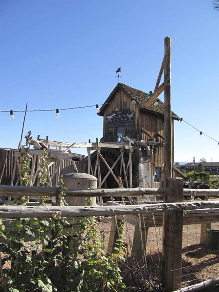 Old wooden building with water wheel and Long Rifle sign, rustic log fence