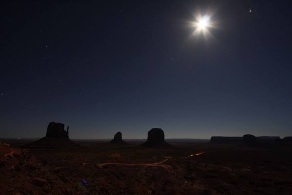 Full moon rising above the sandstone buttes of Monument Valley at night
