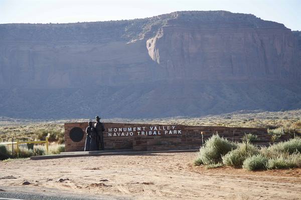 Stone entrance sign of Monument Valley Navajo Tribal Park before a towering mesa
