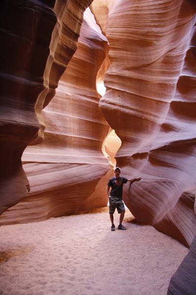 Tourist among the wavy sandstone walls of Antelope Canyon, golden light