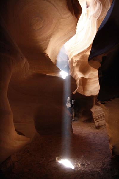 Light beam inside Antelope Canyon, tourists among sculpted sandstone walls