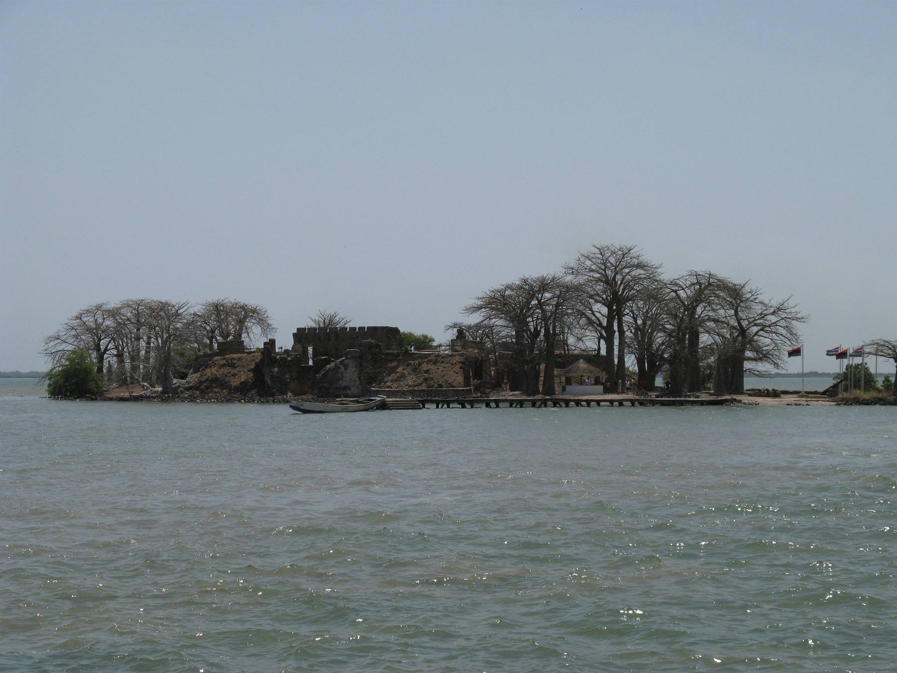 Colonial ruins and baobab trees on Kunta Kinteh Island, boat moored at pier