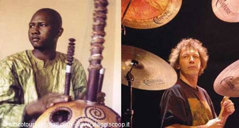 Kora player in green boubou beside a drummer behind his cymbals