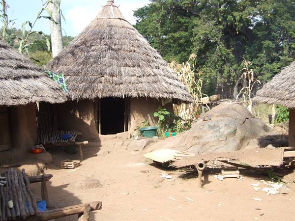 Round huts with thatched roofs and mud walls, packed-earth courtyard
