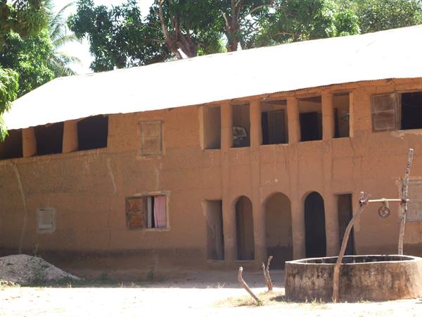 Cement well in courtyard in front of mud-brick house with tin roof