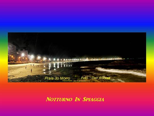 Night at Praia do Morro: people on the beach, streetlights glowing over the ocean