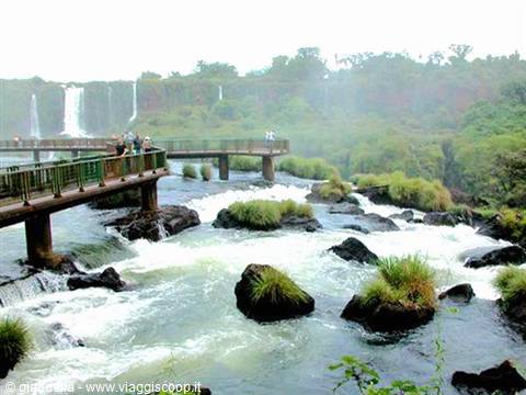 Metal walkways above Iguazú Falls, tourists watching rapids among rocks