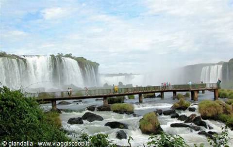 Wooden walkway over Iguazú Falls among rocks and mist