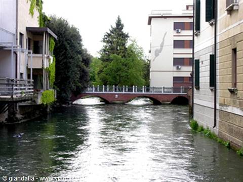 Three-arched brick bridge over an urban canal between buildings, Treviso