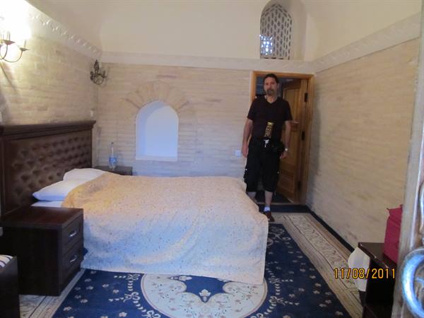 Man standing by the bed in a traditional room with pale brick walls