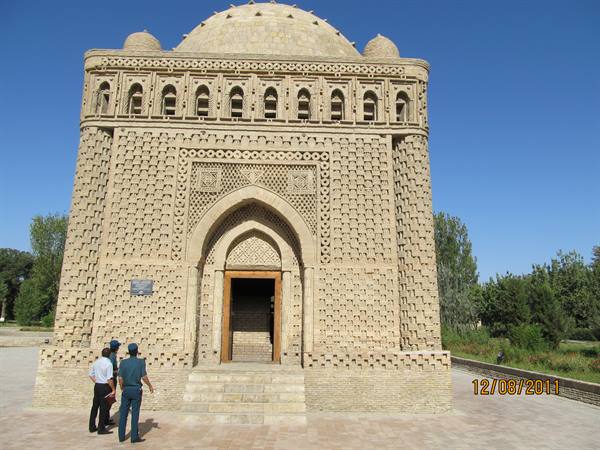 Tourists before the Samanid Mausoleum in Bukhara, woven brickwork under blue sky