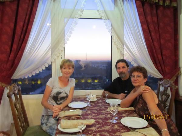 Three smiling people at a set table by a restaurant window