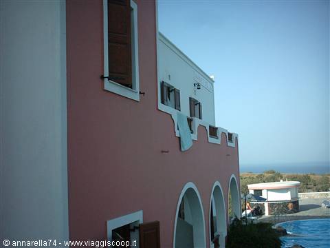 Pink and white hotel arches with pool, sea in the background