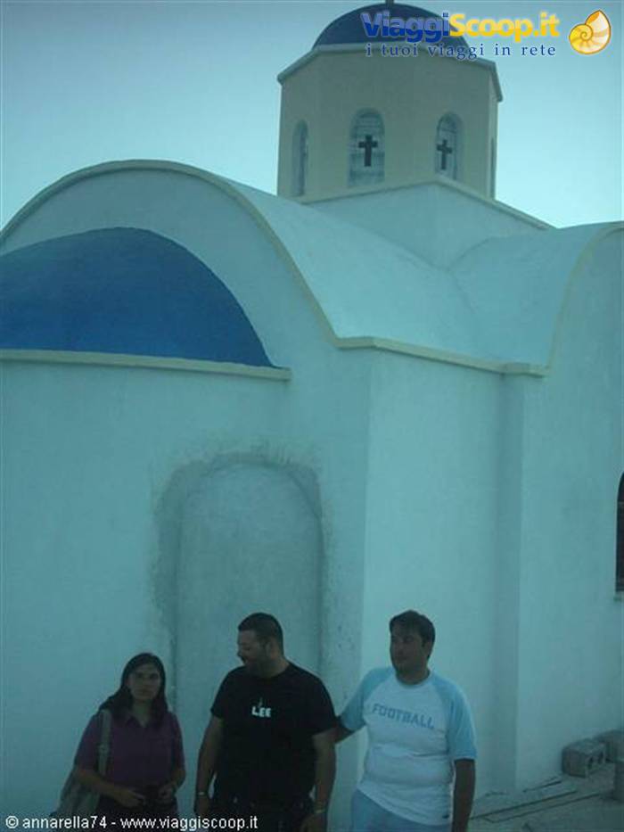 Tourists in front of white church with blue domes in Santorini